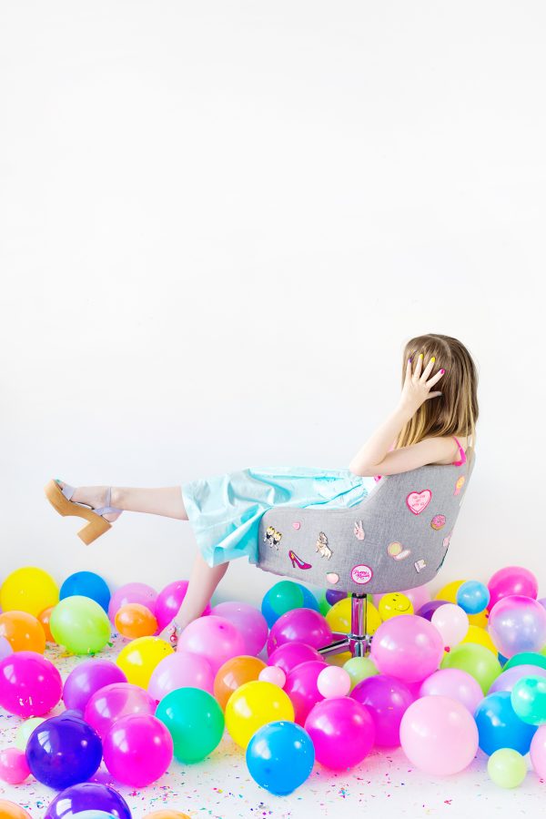 Someone sitting in a desk chair and balloons under them