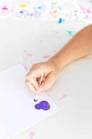 Someone painting purple on a paper