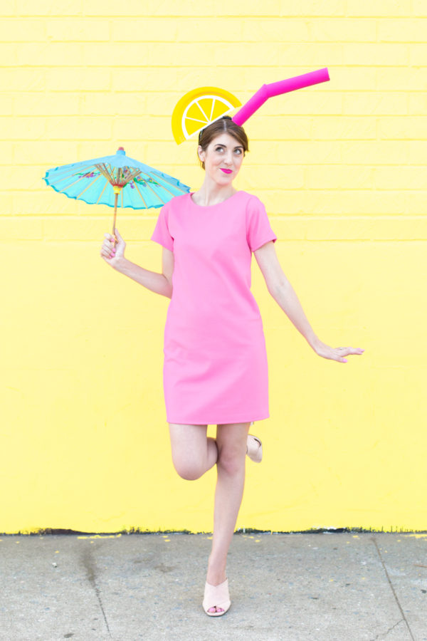 A woman in a tropical drink costume in front of a yellow wall