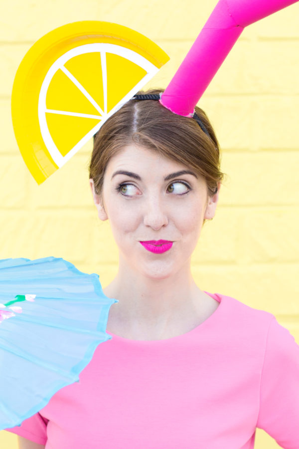 A woman in a pink shirt standing in front of a yellow wall