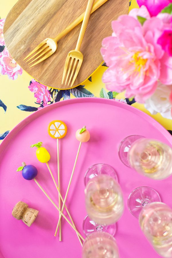 A pink plate with glasses and stirrers