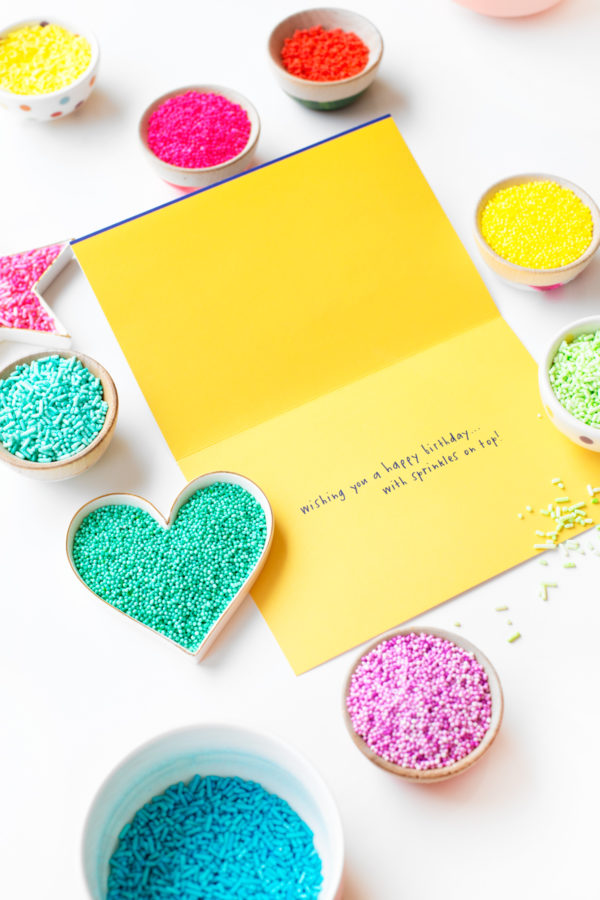 A yellow card and containers of sprinkles 