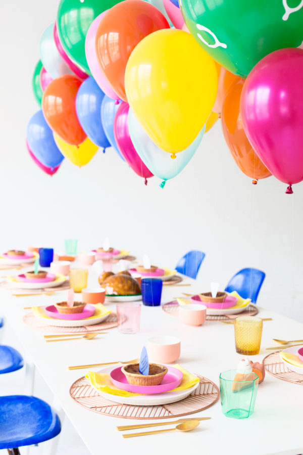 A table with plates, cups, and balloons