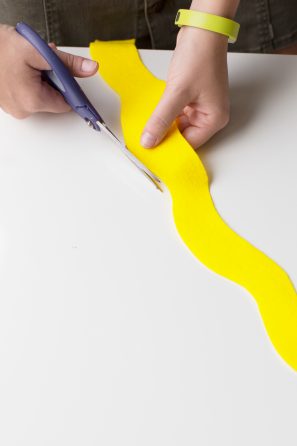 Someone cutting yellow fabric with scissors