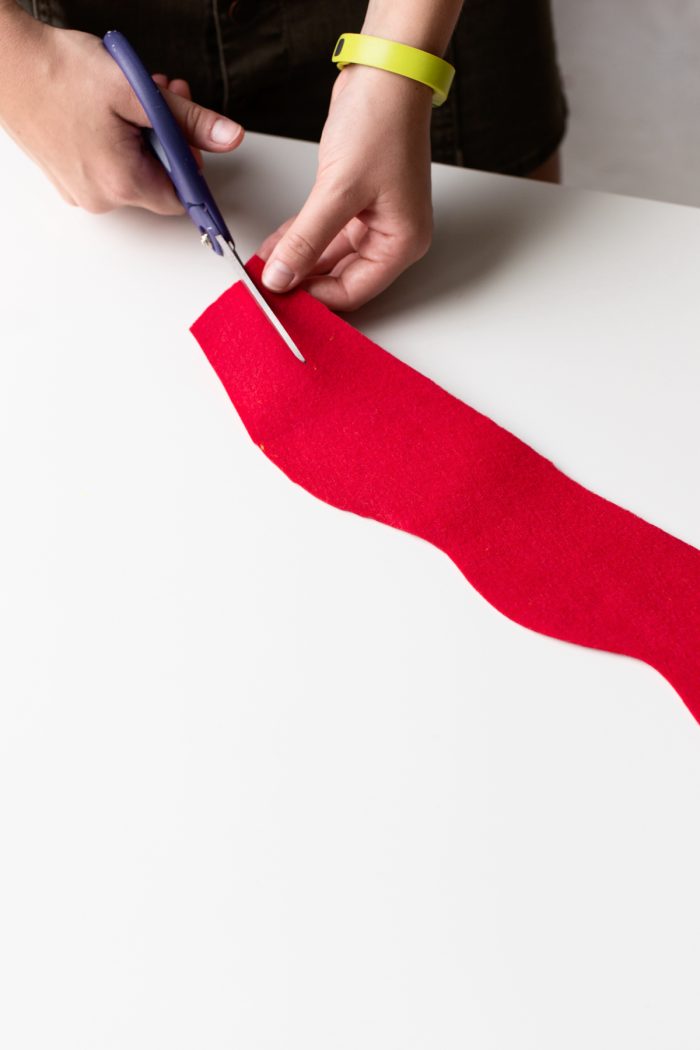 Hand cutting a piece of red felt. 