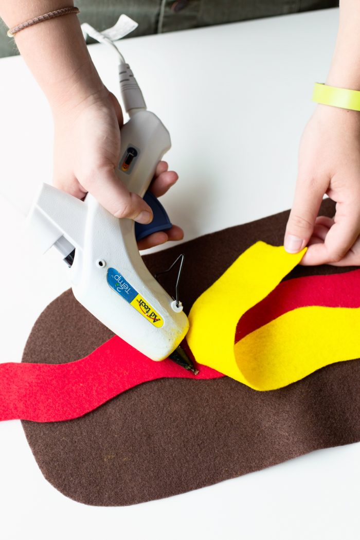 Someone gluing yellow felt to brown and red felt.