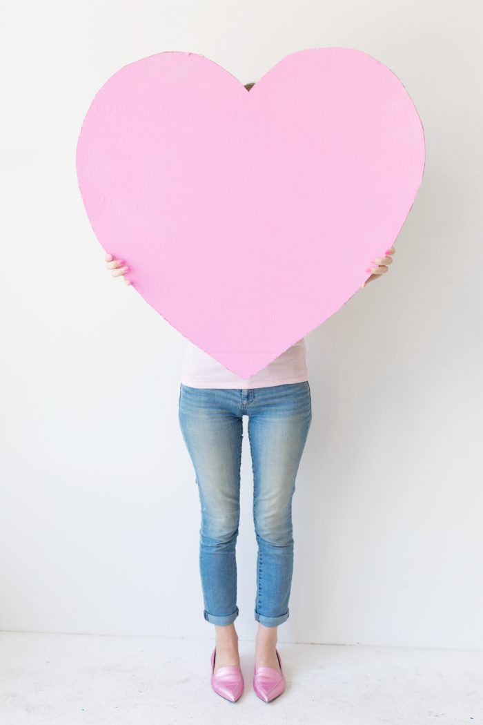 A woman holding a giant pink heart