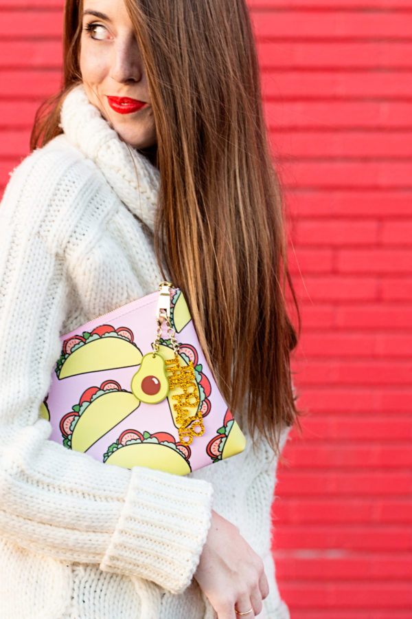 A woman wearing a white sweater and holding a taco clutch