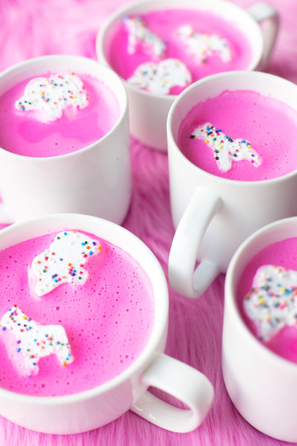 A bunch of mugs with a pink liquid and animal marshmallows 