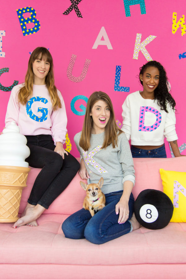 Three people sitting on a couch wearing sweatshirts 