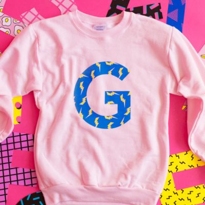 A pink crewneck with a G on it