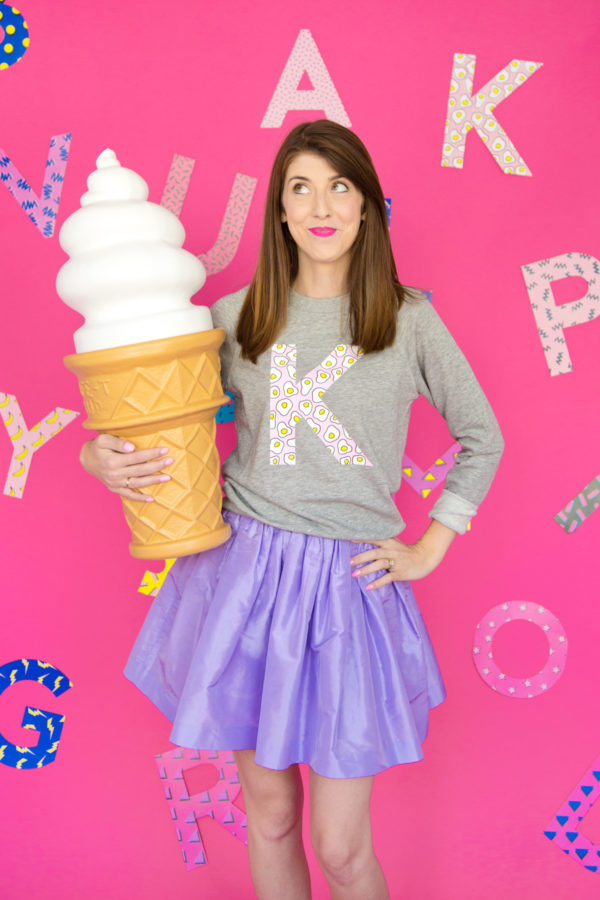 A woman wearing a K crewneck and holding a big ice cream