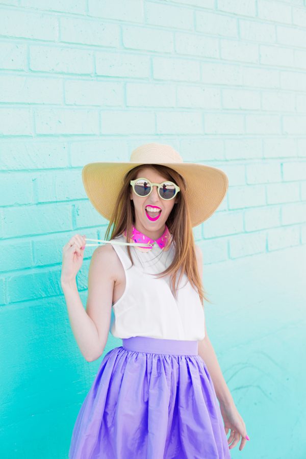 A woman wearing a hat standing in front of a blue wall