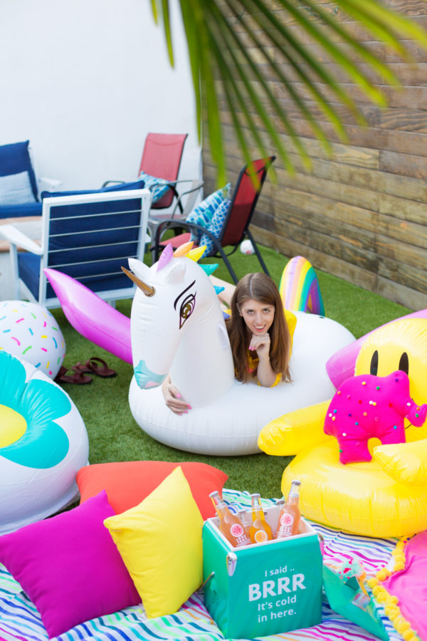 A woman sitting on a unicorn pool floatie 