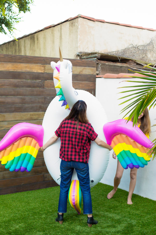 A woman holding a unicorn floatie 