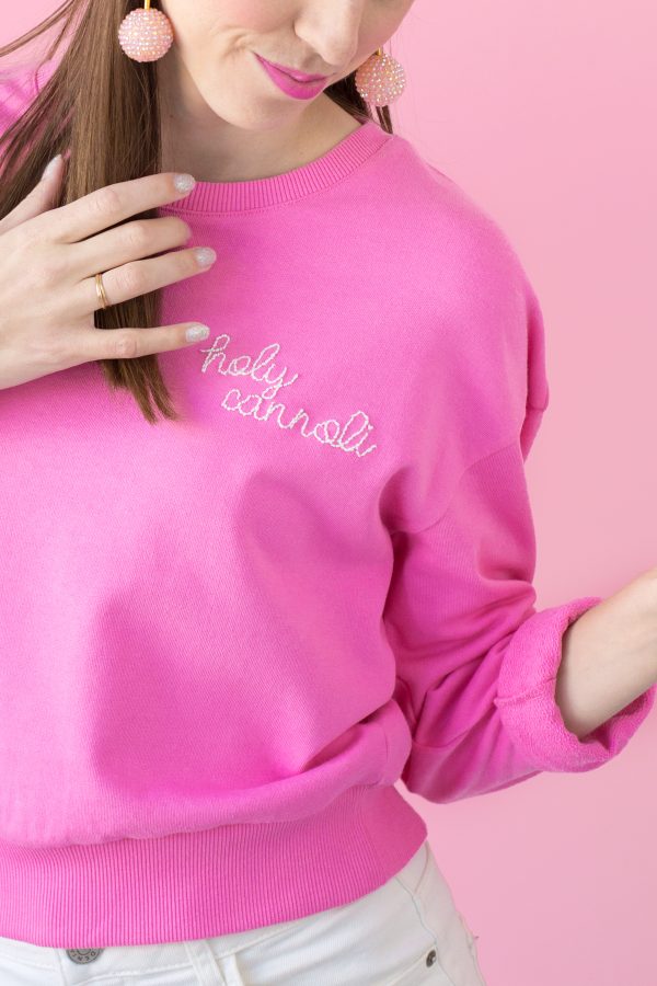 The corner of a pink crew neck with embroidered words on it