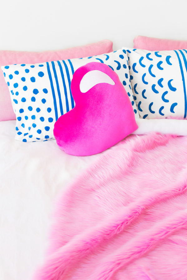 A bed with pillows and a pink blanket