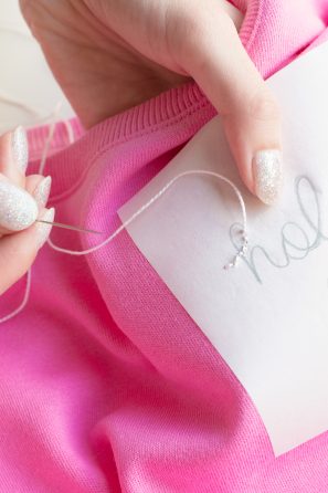 Someone sewing something onto a pink shirt