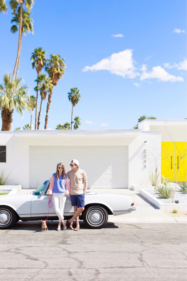 Two people standing in front of a car in front of a house