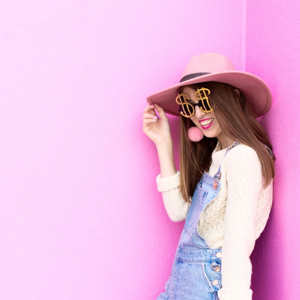 A woman wearing a hat in front of a pink wall