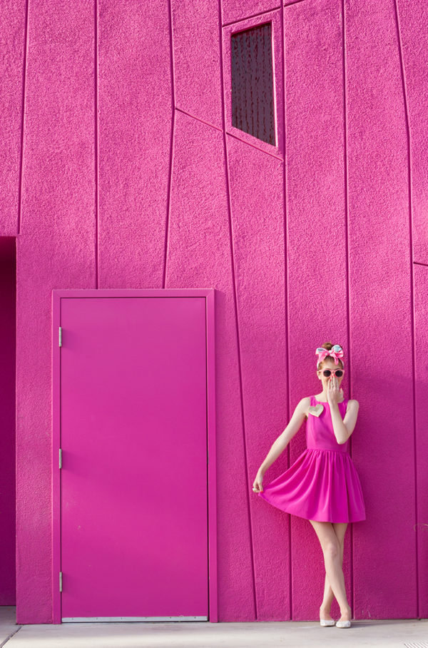 A woman in a pink dress standing in front of a pink wall