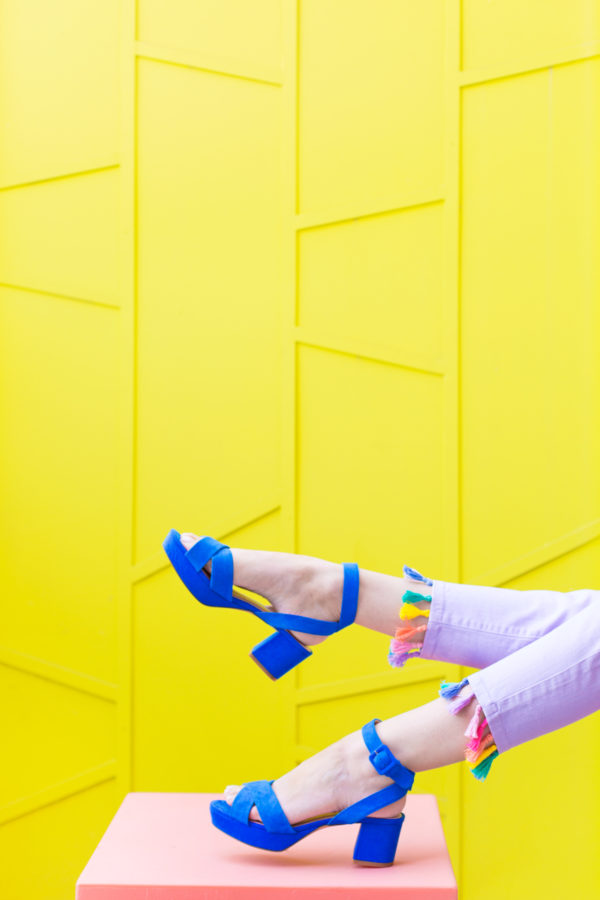 Blue heels in front of a yellow wall