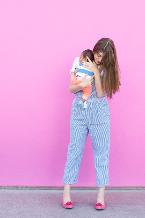 A woman standing in front of a pink wall