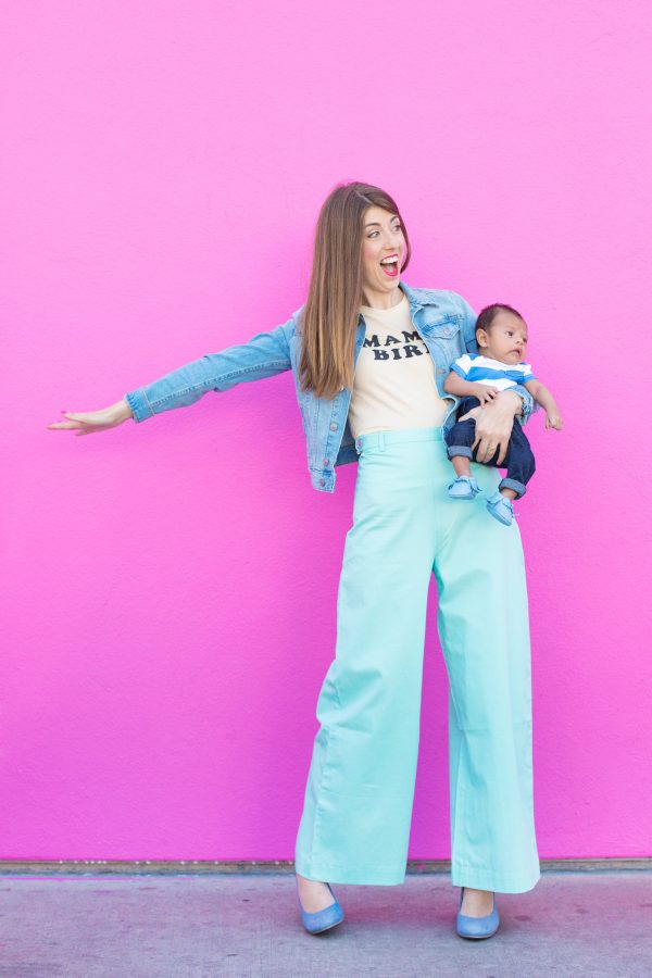 A woman holding a baby in front of a pink wall