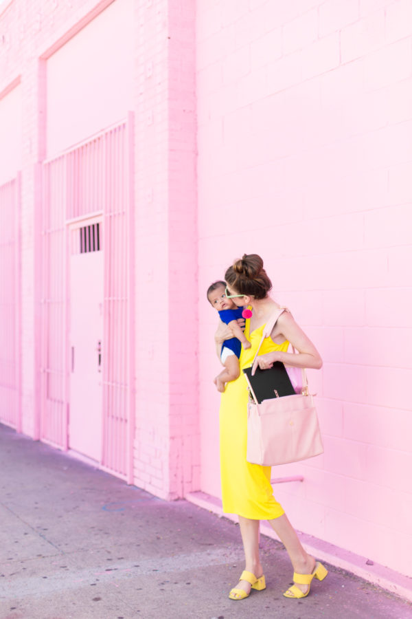 Someone holding a baby in front of a pink wall