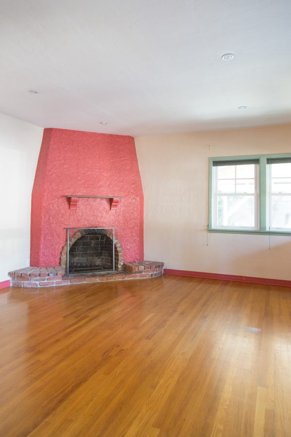 A large empty room with a pink fire place