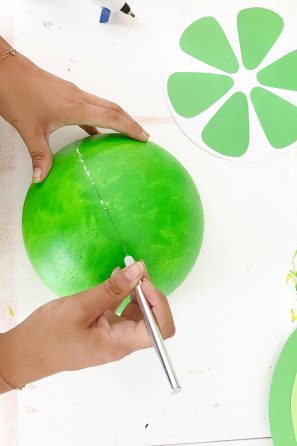 Someone cutting a green sphere 