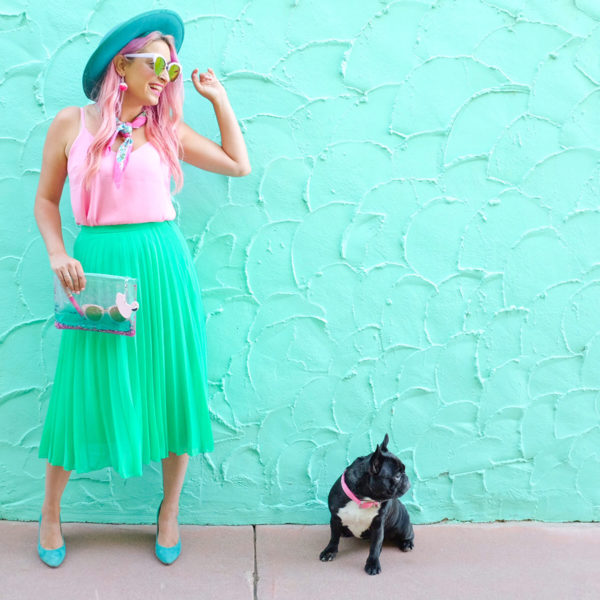 A woman standing in front of a blue wall next to a dog