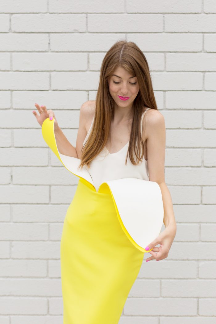 A woman standing in front of a brick wall, with Banana Costume