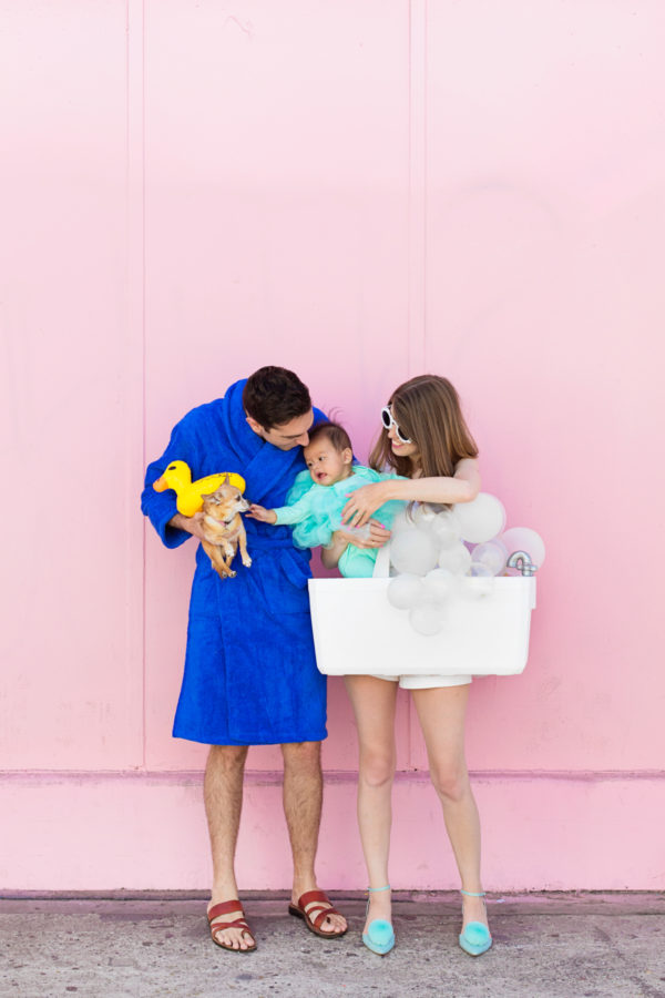 A family dressed in costumes in front of a pink wall