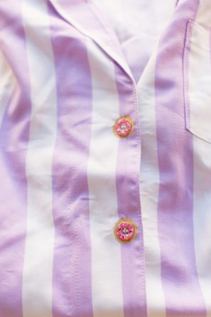 A close up of a purple and white striped shirt with buttons 