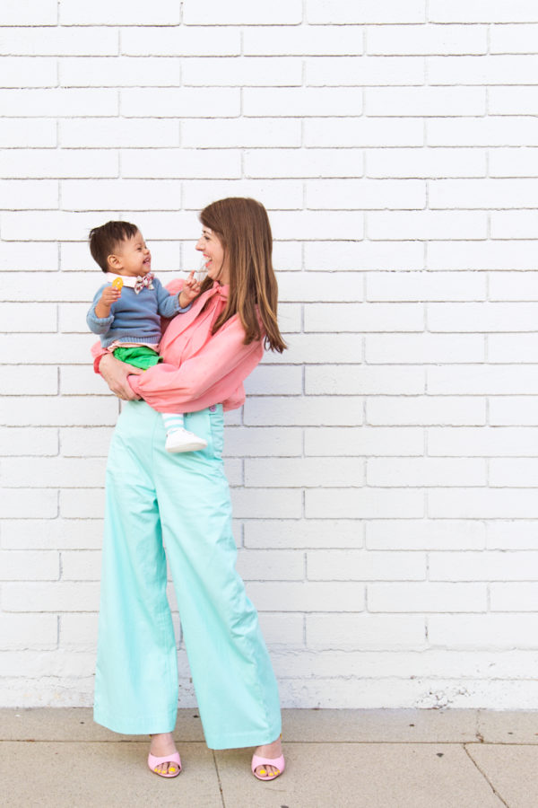 A woman holding a little boy in front of a white wall