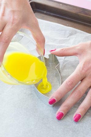 Someone pouring yellow liquid into a tin frame