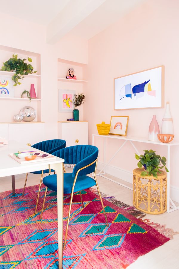 A room with a colorful rug and blue chairs