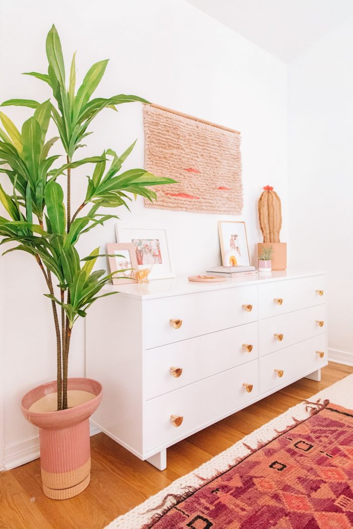 A room with a white dresser and plants