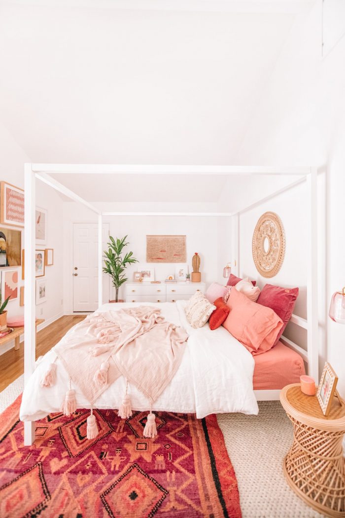 A bedroom with pink blankets and pillows