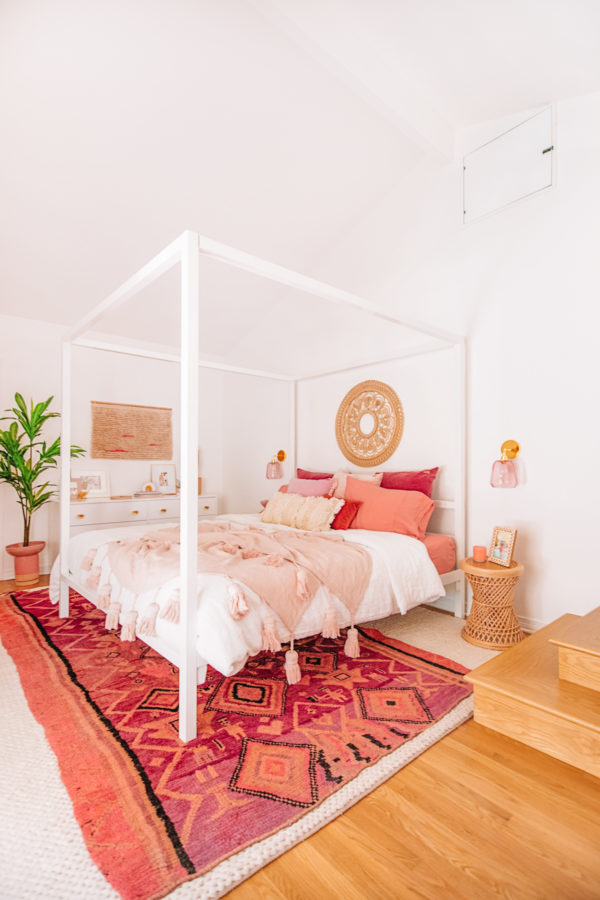 A bedroom with a white bed and pink decor
