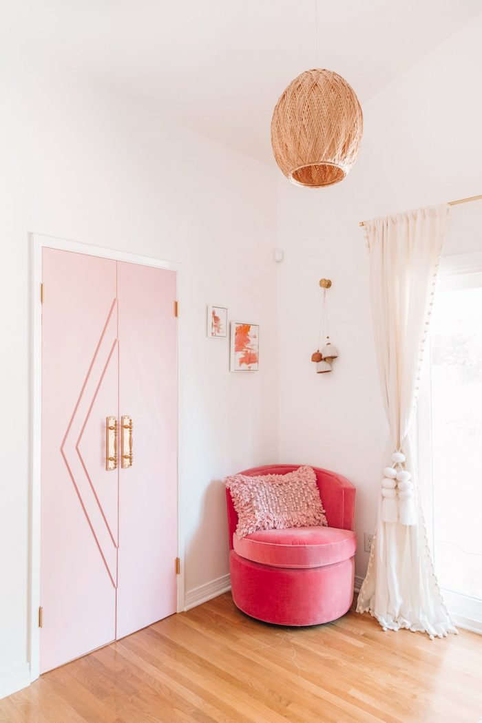 A room with a pink chair and pink door