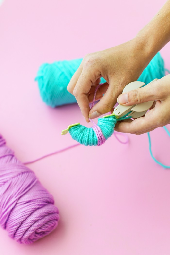 Blue and purple yarn wrapped around a Pom Pom maker