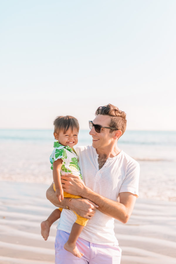 A man holding a a little boy on the beach