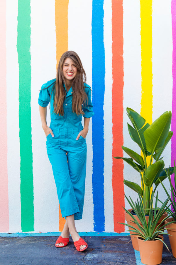 A woman standing in front of a rainbow wall