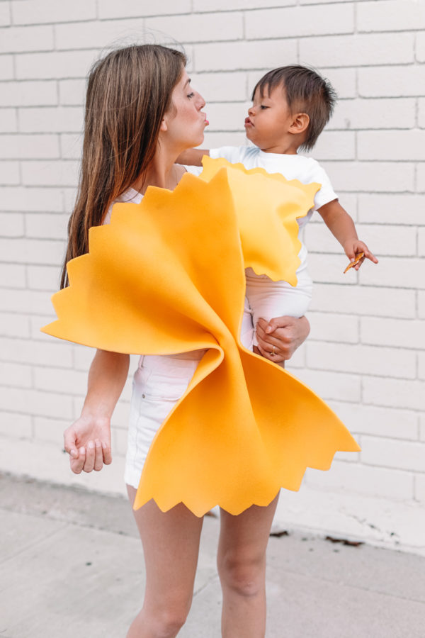 A woman holding a baby dressed as pasta