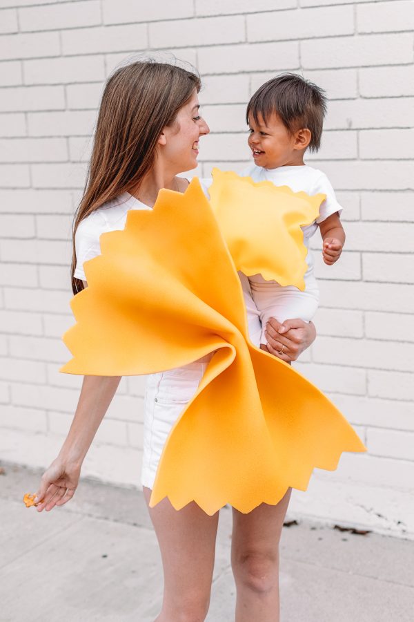 A woman holding a child dressed up as pasta