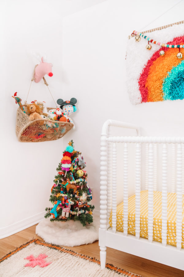 A mini Christmas tree next to a crib