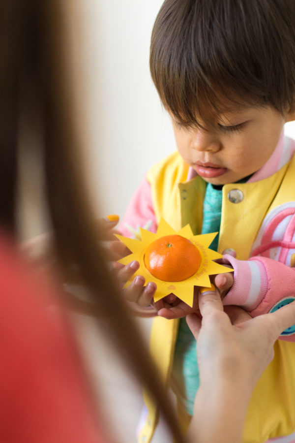 A small child is holding an orange