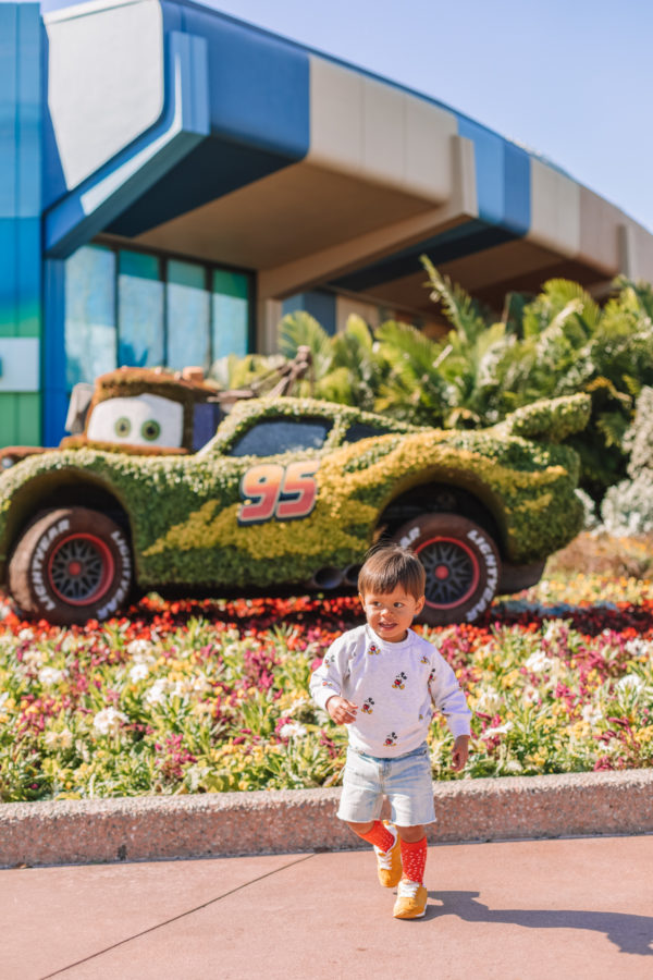 A boy standing in front of a car